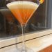 A martini-style cocktail in three layers: white, yellow, orange, with a candy corn garnish.